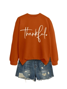 Flat lay detail of an orange crewneck sweatshirt featuring a white thankful print