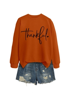Detail of orange sweatshirt with thankful print paired with ripped denim shorts