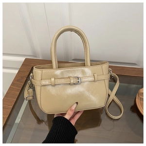 Detail of beige crossbody bag with silver buckle strap and glossy faux leather texture