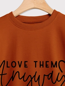 Detail of caramel crewneck sweatshirt featuring ribbed collar and Love Them Anyway print