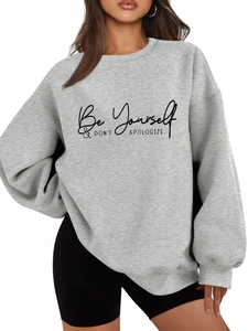 Detail of grey crewneck sweatshirt featuring Be Yourself & DON'T APOLOGIZE text print