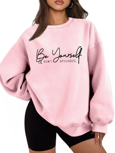 Detail of light pink sweatshirt featuring black 'Be Yourself' slogan and ribbed cuffs