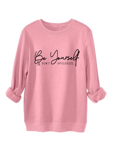 Pink crewneck sweatshirt detail featuring black Be Yourself and Don't Apologize slogan print