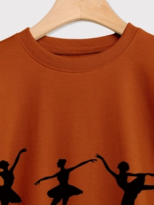 Detail of dark orange sweatshirt showing ribbed neckline and black ballet dancer silhouettes