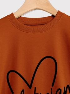 Close-up of caramel orange sweatshirt neckline featuring black heart line art print