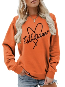 Detail of orange long-sleeve sweatshirt with Esthetician lettering and heart graphic