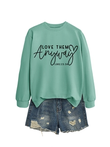 Detail of mint green crewneck sweatshirt and distressed denim shorts with graphic text