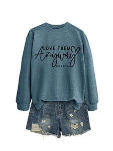 Detail of blue crewneck sweatshirt with Love Them Anyway text and ripped denim shorts