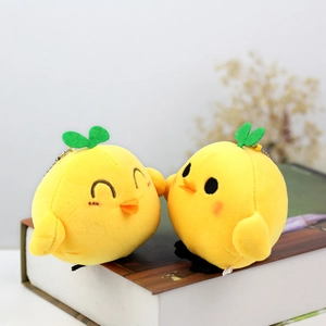 Close-up of cute yellow chick plush keychains with green sprouts on a dark book cover