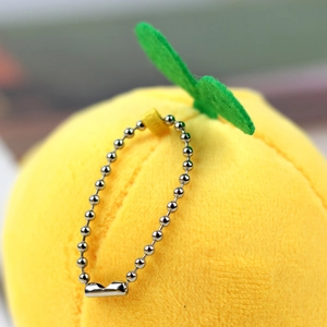 Macro detail of a soft yellow plush fruit charm with green leaf and silver bead chain