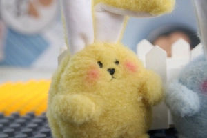 Close-up of yellow plush rabbit with embroidered heart nose and soft long fur texture