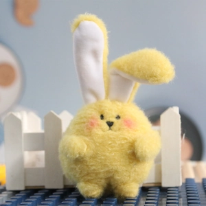 Close-up of a soft yellow plush bunny with long ears on a creative blue brick background