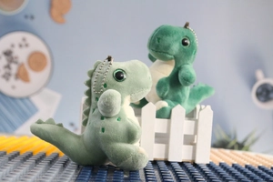 Detail of green plush dinosaur keychains with metal chains and soft fabric texture
