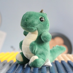 Detail of green plush dinosaur keychain with metal bead chain and washing label