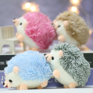 Close-up of four colorful plush hedgehog keychains in a cozy, warm decorative setting