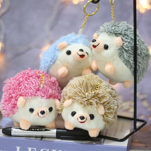 Detail of four colorful hedgehog plush keychains in pink, blue, green and khaki on a desk