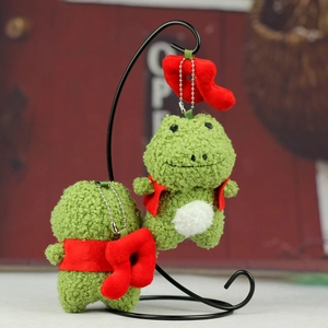 Pendentif grenouille en peluche verte avec gilet rouge sur un support métallique