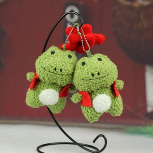 Détail du porte-clés grenouille en peluche verte avec écharpe rouge et étoile en polaire