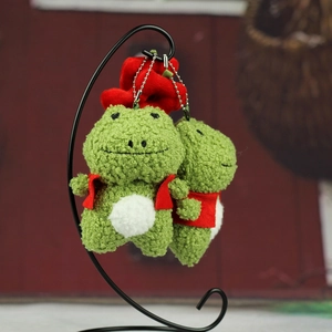 Vue détaillée de porte-clés grenouille en peluche verte avec gilets rouges et chaînes