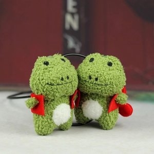 Détail d'un pendentif grenouille en peluche verte avec sac à dos rouge en velours doux
