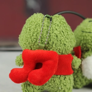 Gros plan d'un porte-clés grenouille en peluche verte avec une note de musique rouge