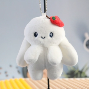 Detail of white plush bunny keychain with red strawberry accessory and metal chain