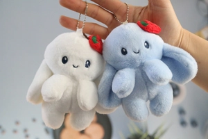 Detail of cute plush bunny charms in white and blue colors with strawberry accents