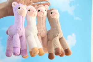 Detailed view of colorful plush alpaca keychains in purple, white, pink and brown fur