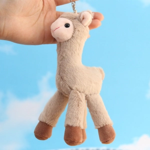Cute alpaca plush keychain with soft beige fur and metal chain against a blue sky background