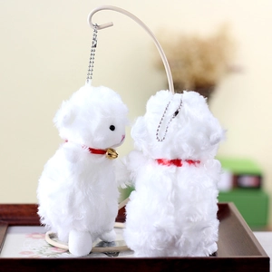 Close-up of white plush lamb keychain with red ribbon and golden bell details