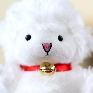 Close-up of white plush lamb keychain with a red satin collar and golden bell