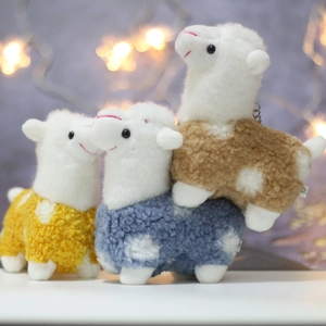 Close-up of three colorful llama plush pendants in yellow, blue and brown curly fleece