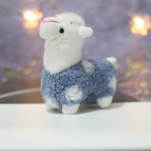 Close-up of white plush alpaca doll with blue dotted body and soft curly fur texture