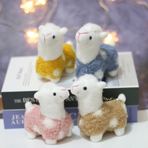 Detail of four colorful plush alpaca keychains on books with warm bokeh background