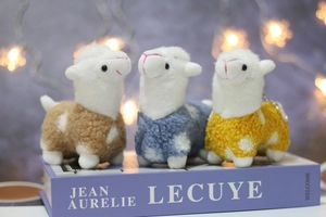 Close-up of soft plush alpaca pendants in blue, brown, and yellow with metal keychains