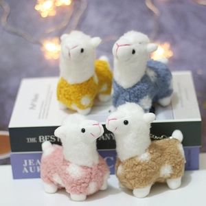 Detail of cute alpaca plush pendants in four colors with curly faux fur and metal keychains