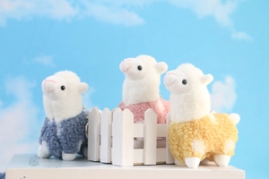 Close-up of cute alpaca plush pendants in blue, pink, and yellow knitted coats