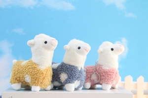 Detailed view of colorful plush alpaca pendants in yellow, blue and pink with metal keychain