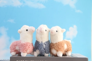 Detailed close-up of cute plush alpaca dolls in pink, blue, and brown curly faux fur textures
