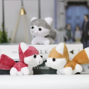 Three cute husky plush pendants in red, brown, and grey with fluffy tails on decor books