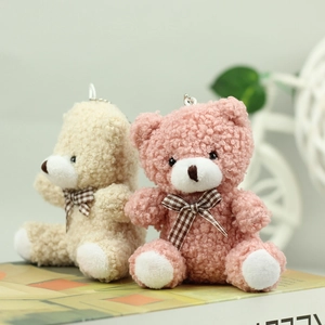 Close-up of pink and cream teddy bear plush charms with plaid bows and metal chains