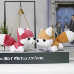 Close-up of pink and brown plush fox charms with metal chains on a vintage book