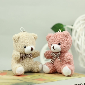 Close-up of cute plush teddy bear pendants in beige and pink with checkered bowties