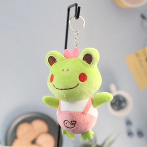 Detail of plush frog keychain with pink overalls and metal ring for bags