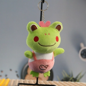 Detailed plush frog keychain with pink heart decor and whale pattern overalls on display