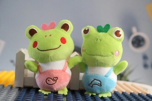 Detail of plush frog keychains wearing colorful overalls with cute embroidery