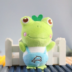 Close-up of cute green frog plush keychain with blue overalls and embroidered details