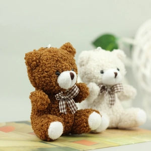 Cute teddy bear plush keychains in brown and beige with plaid bows on books
