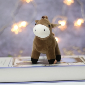 Close-up of a soft brown donkey plush keychain standing on a book with bokeh lights