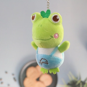 Detail view of plush frog keychain with blue dolphin overalls and green heart headpiece